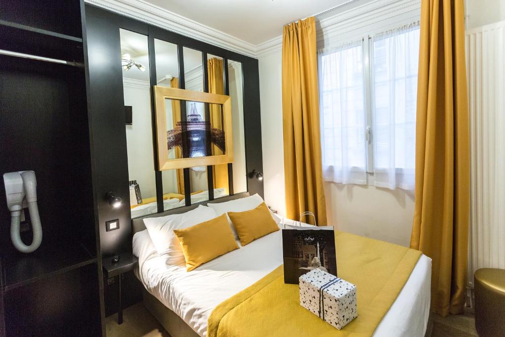 a bedroom with a bed with yellow curtains at Pratic Hotel in Paris