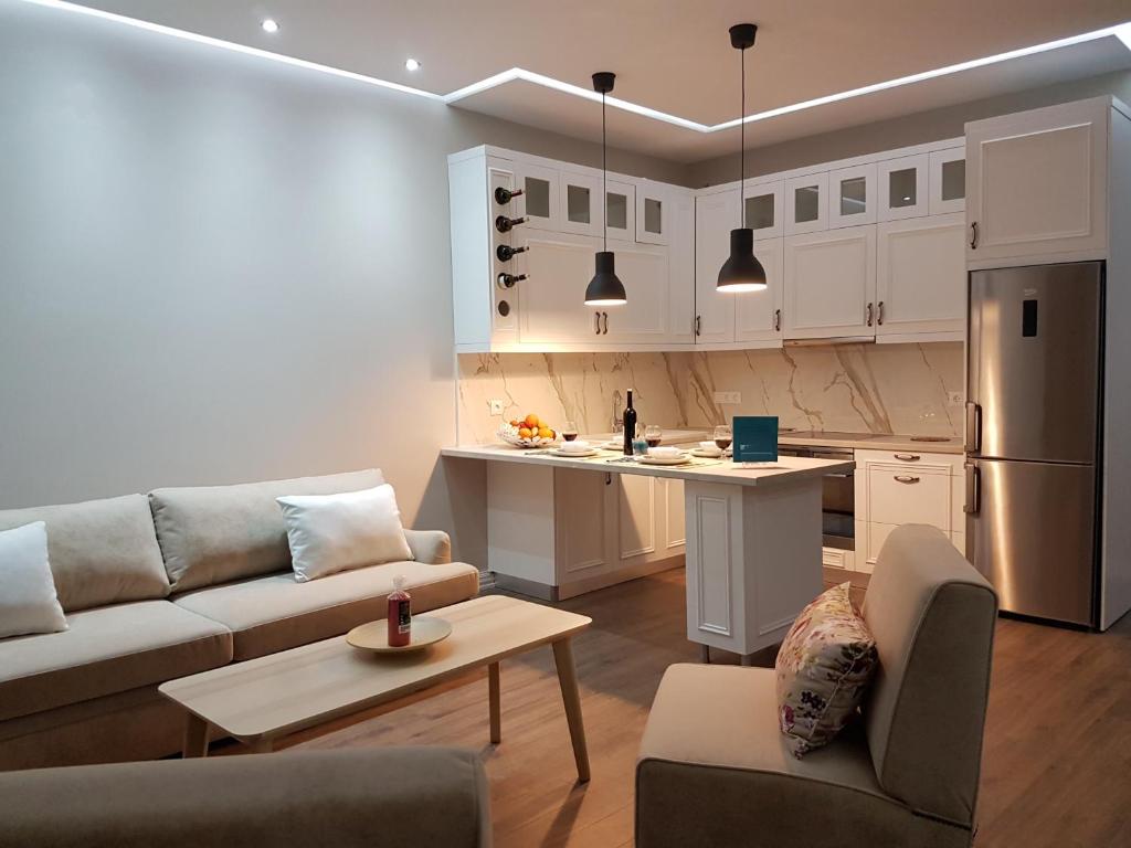 a living room with a couch and a kitchen at Great Alexander Suites in Sarandë