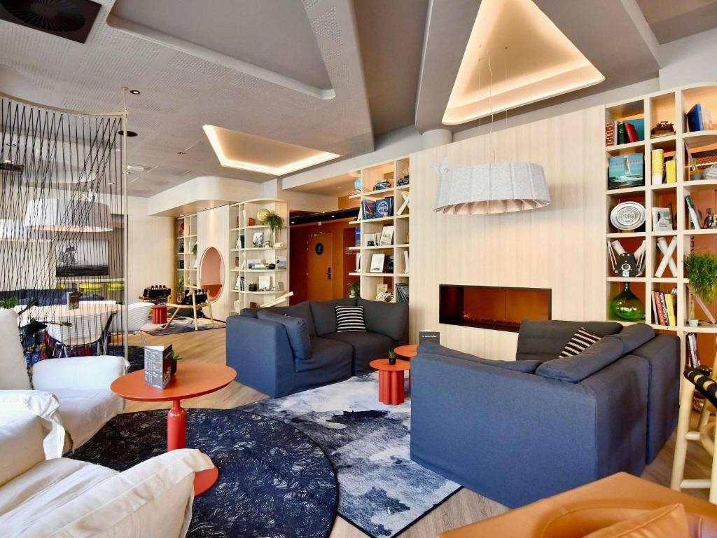 a living room with blue couches and a fireplace at ibis Styles Brest Centre Port in Brest