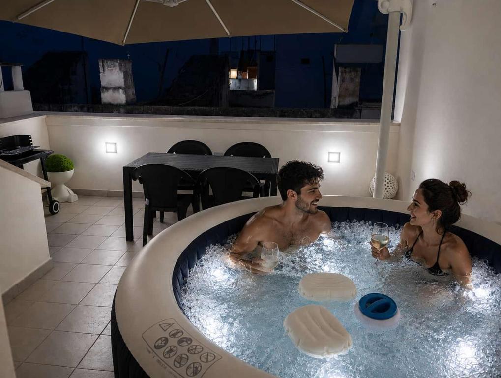 a man and a woman sitting in a jacuzzi at Ranieri rooms & relax stella in Mola di Bari