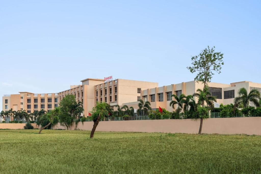 a building with palm trees in front of a field at Ramada by Wyndham Bodh Gaya Mahabodhi in Bodh Gaya
