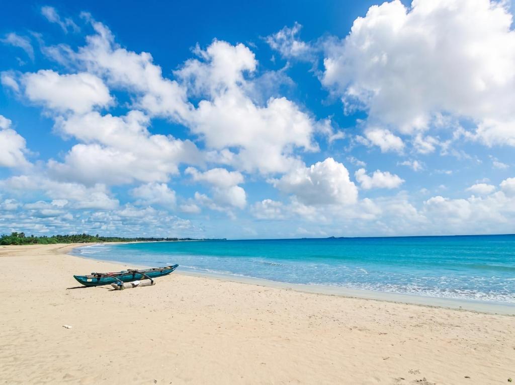 a boat sitting on a beach next to the ocean at Bliss Bay Beach Resort & Spa in Nilaveli