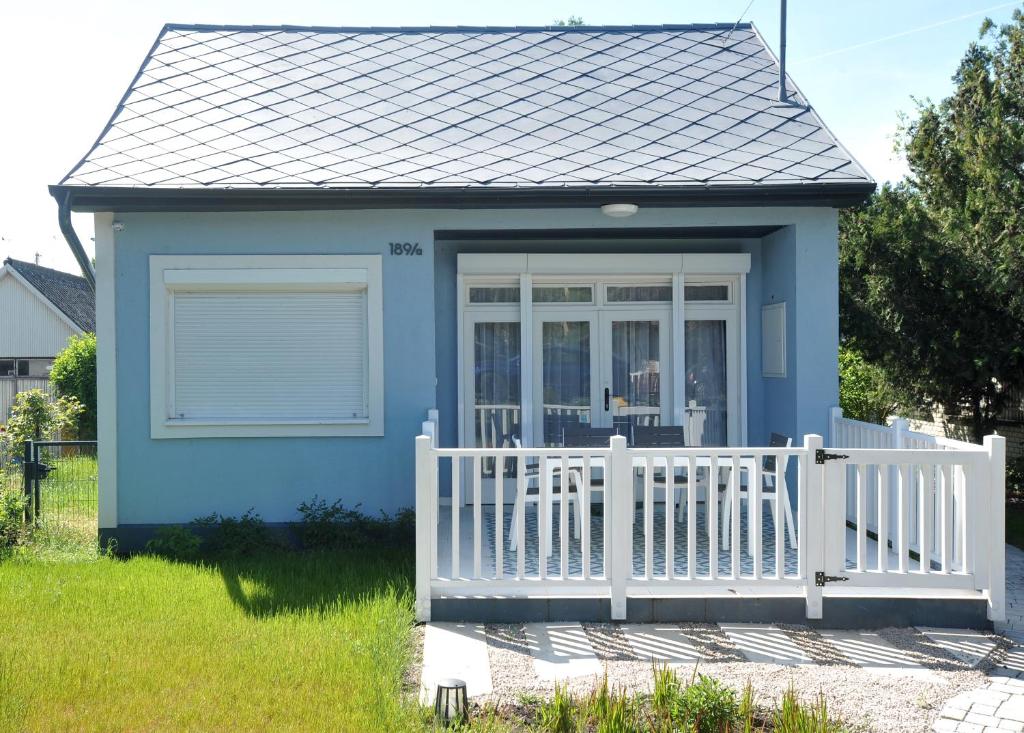 a small blue house with a white fence at LelleBlue Vendégház in Balatonlelle