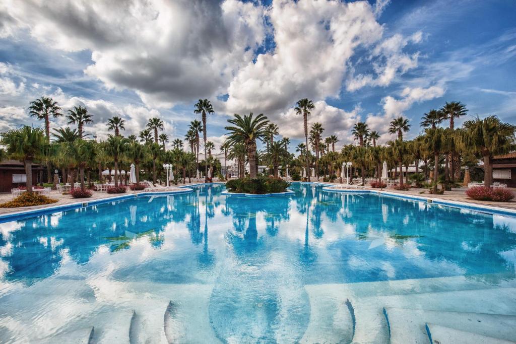 a large swimming pool with palm trees in the background at Hotel Parco dei Principi in Foggia