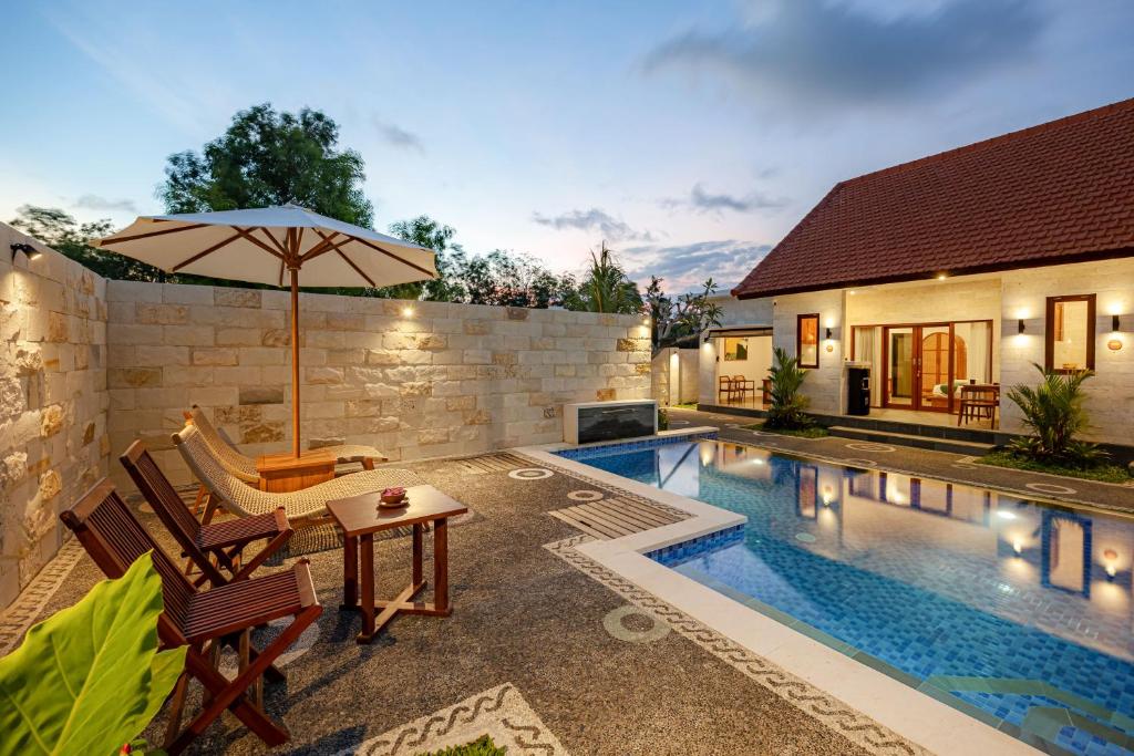 a swimming pool with a table and an umbrella at Cove Tegeh Bila in Ungasan