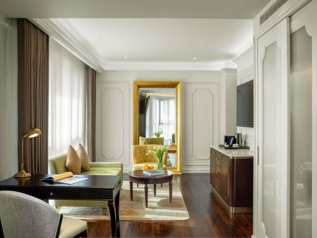 a living room with a green couch and a table at Hotel de l’Opera Hanoi - MGallery in Hanoi