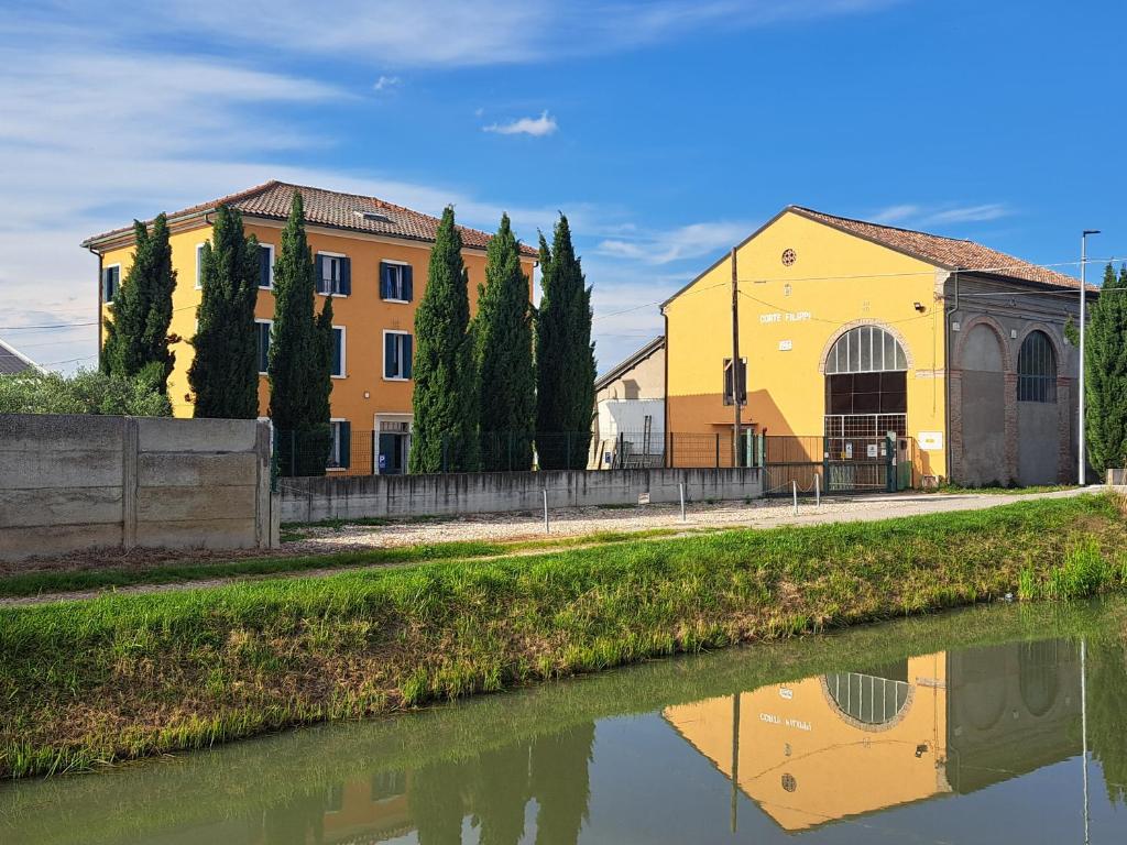 a yellow building next to a body of water at Agriturismo Corte Filippi in Villadose