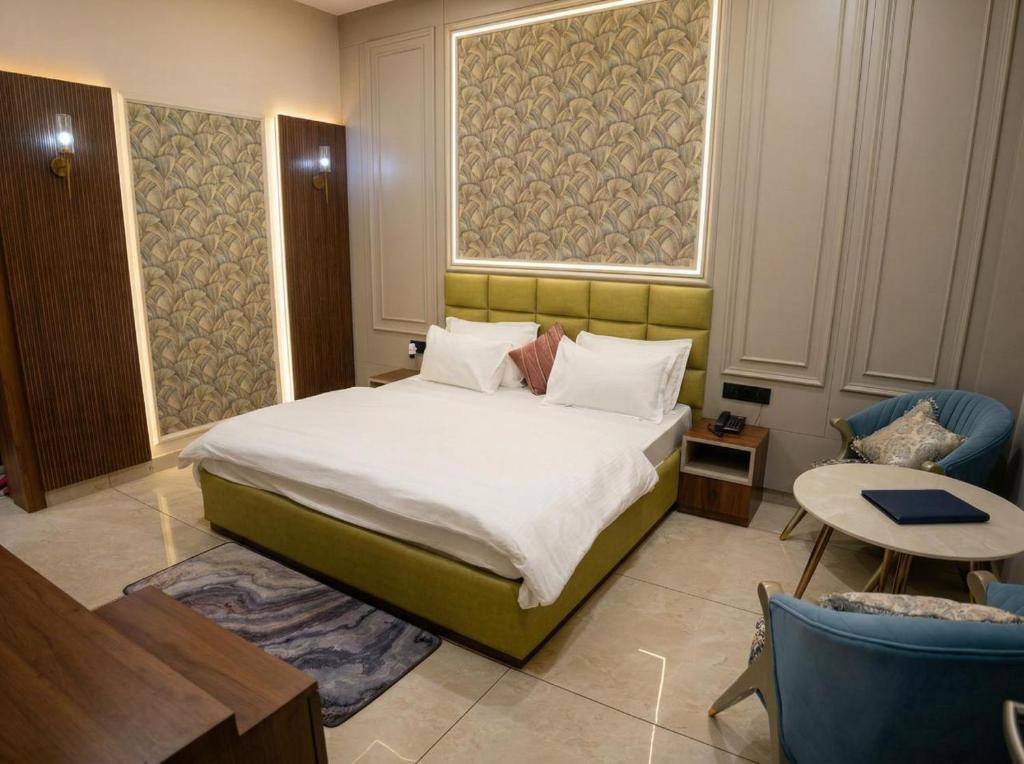a bedroom with a large bed and two chairs at Thejaiparadise by jai hotel in Rohtak