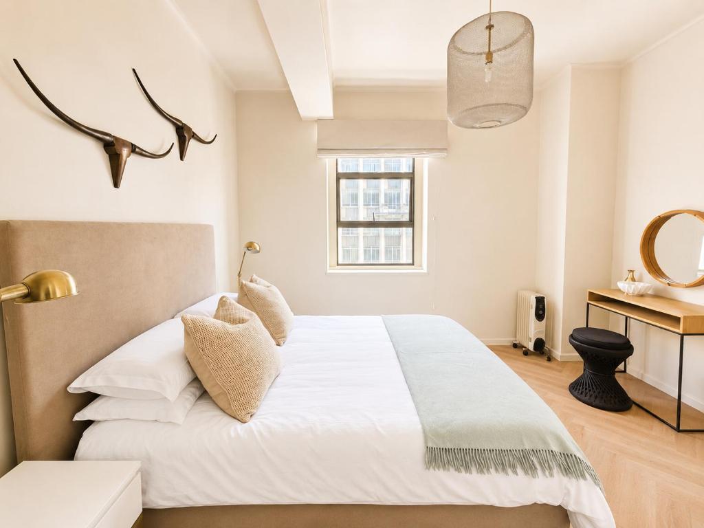 a bedroom with a large white bed and a sink at Cape Central Designer Suite in Cape Town