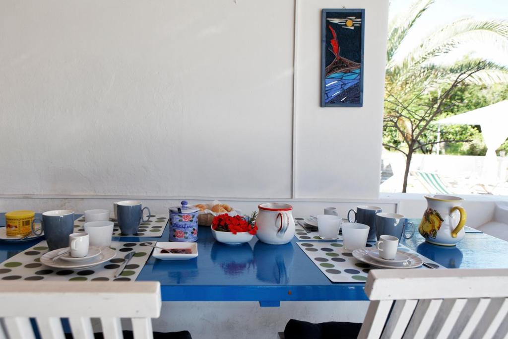 een blauwe tafel met bekers en kommen met eten erop bij Casa Carlotta in Stromboli