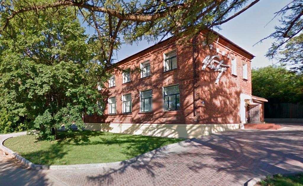 un viejo edificio de ladrillo con un árbol delante de él en Hotel Vintage Sheremetyevo, en Moscú