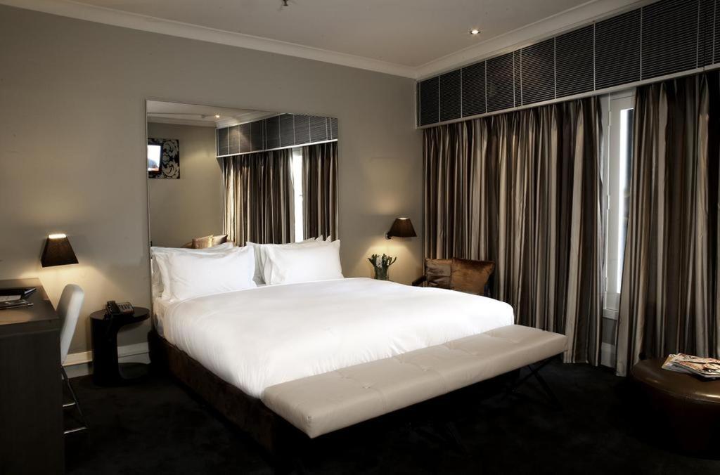 a hotel room with a large white bed and windows at Kirketon Hotel Sydney in Sydney