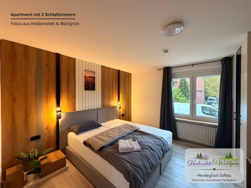 a bedroom with a bed and a large window at Heideglück Soltau - Ferienwohnungen An der Weide in Soltau