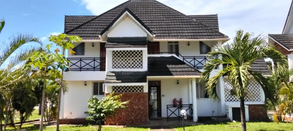 a house with palm trees in front of it at Blue Water Resort in Diani Beach