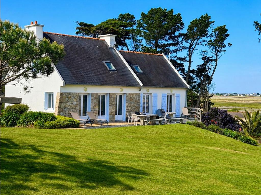 a white house with a picnic table on a lawn at La Bretonne vue mer in Lanmodez