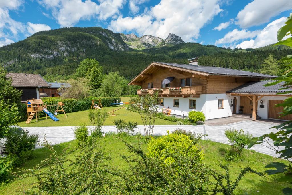 a house with a playground and mountains in the background at Haus Alpenblick Lofer in Lofer