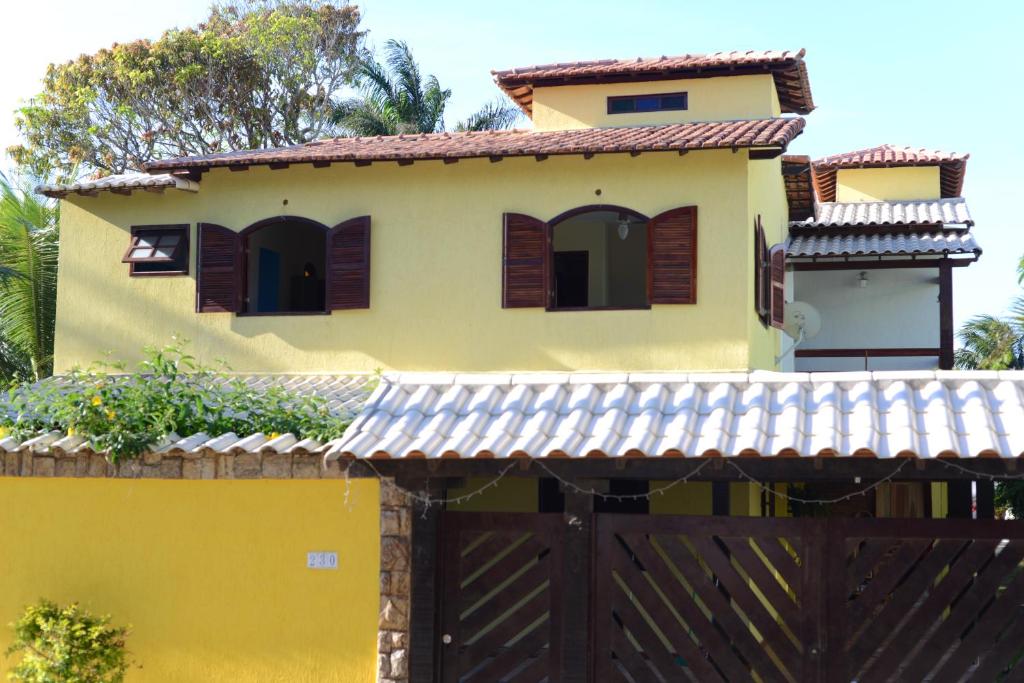 a yellow house with a gate and a fence at Pousada Paraíso de Itaúna in Saquarema