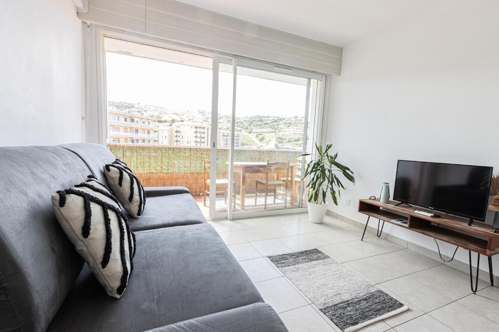 a living room with a couch and a flat screen tv at "U Valincu" – Studio Centre Plage | by Efficios in Propriano