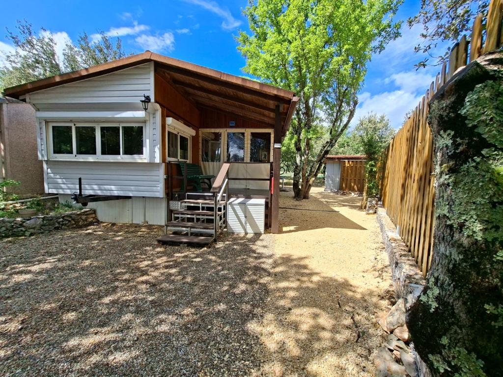 a tiny house with a porch and a wooden fence at Mobile home style maisonnette de vacance in Méjannes-le-Clap