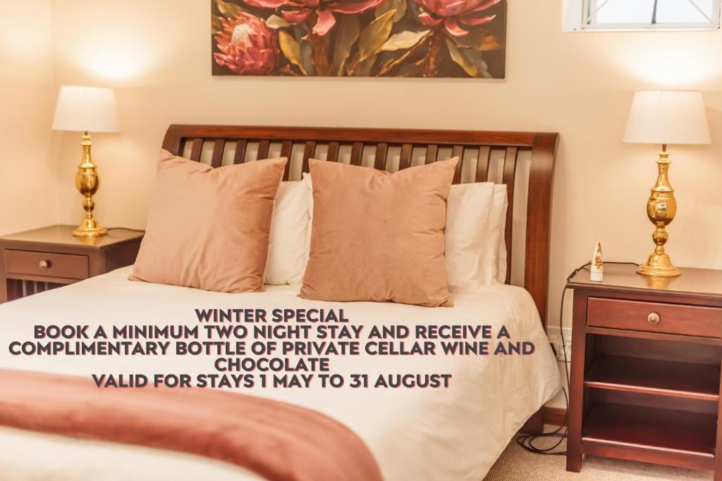 a bedroom with a bed with two night stands and two lamps at Protea Garden Cottage in Stellenbosch