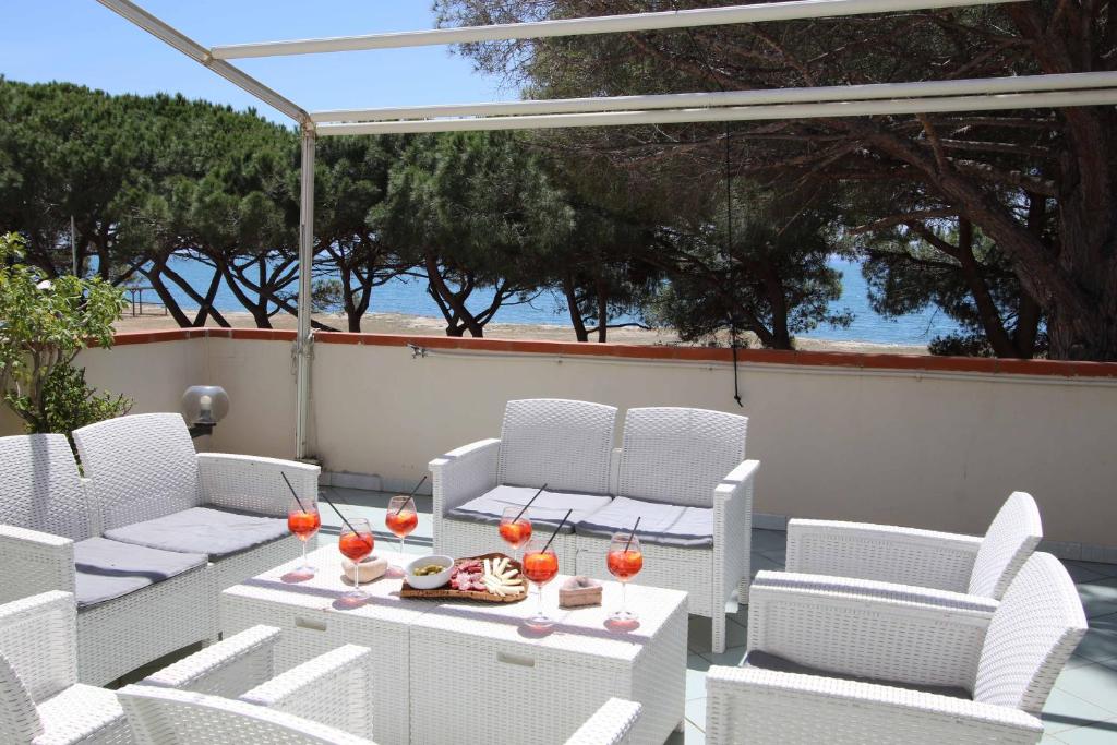 a patio with white chairs and a table with drinks on it at La Terrazza sul Mare - Sa Murta Apartments in Torre Grande