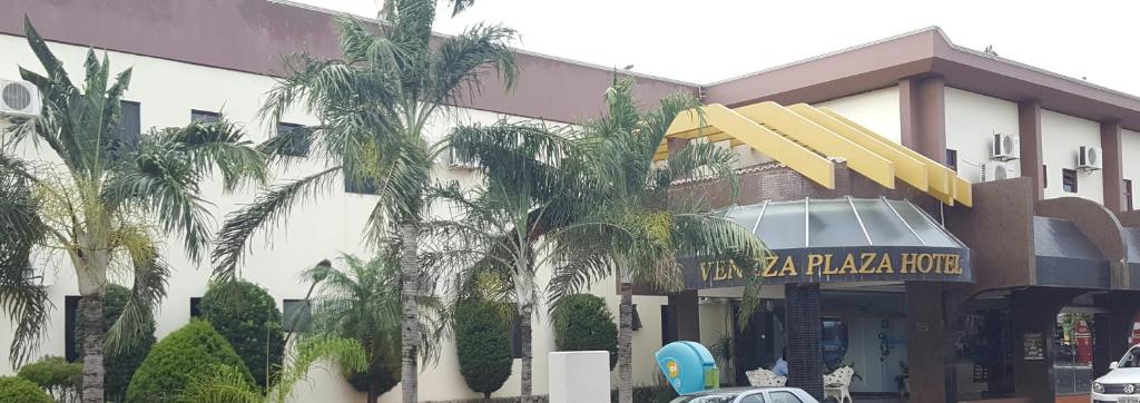 un hotel con palmeras frente a un edificio en Veneza Plaza Hotel, en Gurupi