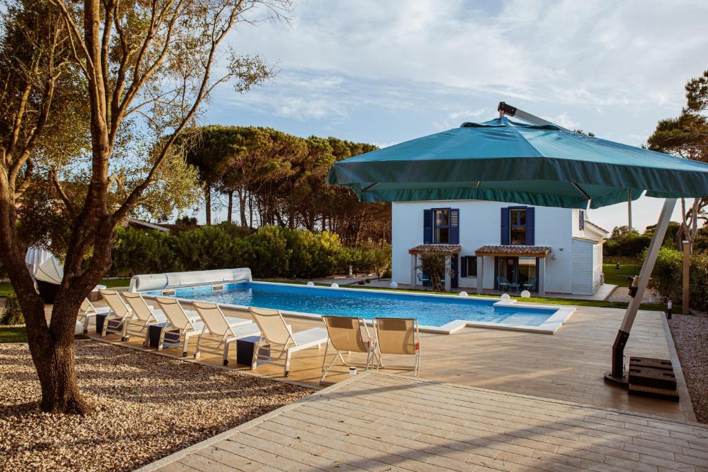 a pool with chairs and a blue umbrella at Villa Rose Sardegna in Calasetta