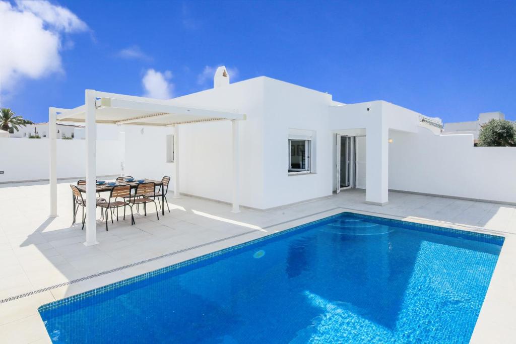 a villa with a swimming pool in front of a house at Villa Izarenar in Cala Blanca