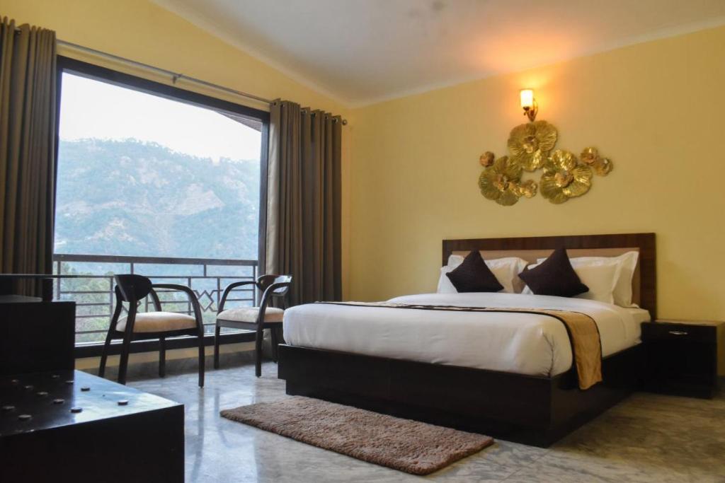 a bedroom with a bed and a balcony with a view at Pinewood Manor in Dagshai
