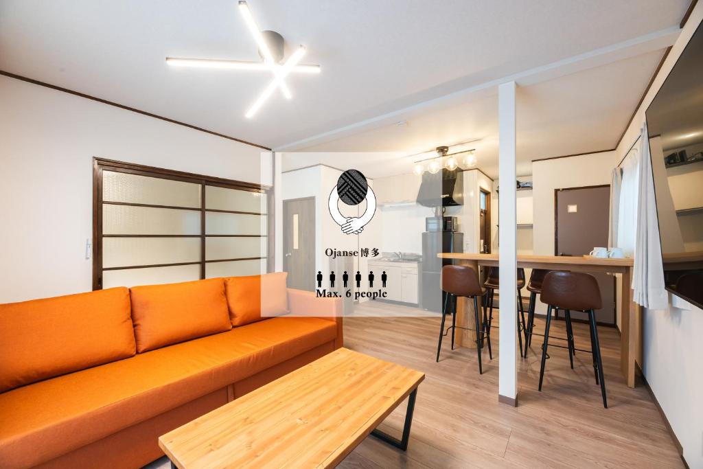 a living room with an orange couch and a table at Ojanse博多 in Fukuoka