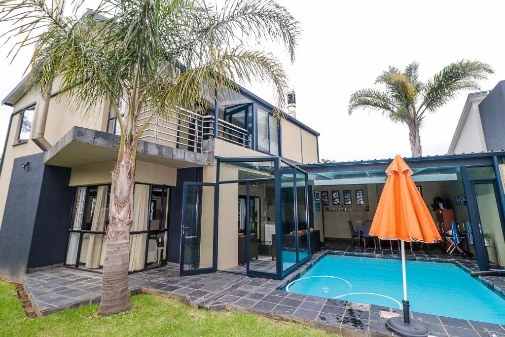 an orange umbrella next to a house with a swimming pool at Heathercreek Accommodation in George