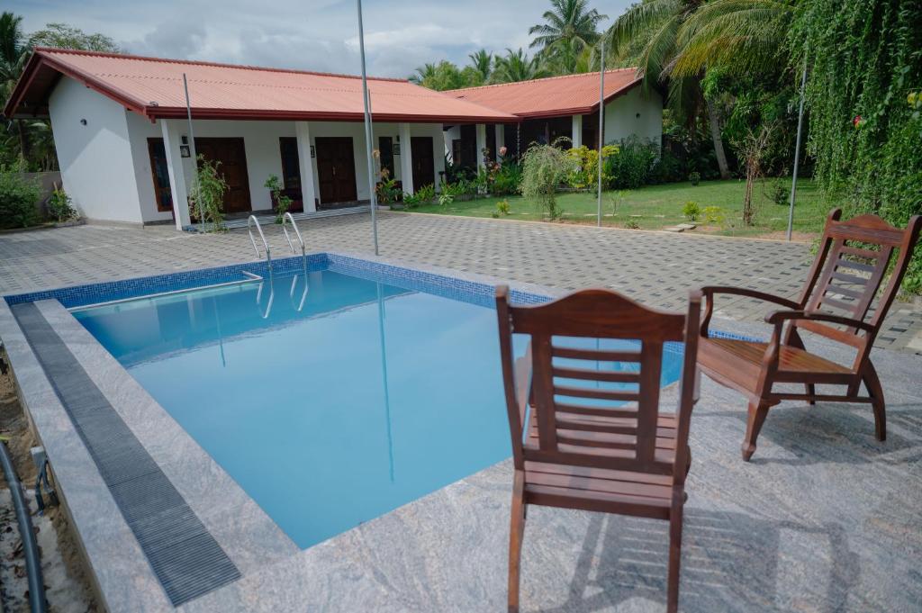 a swimming pool with two chairs and a house at Chamee Oasis Villa in Ranna