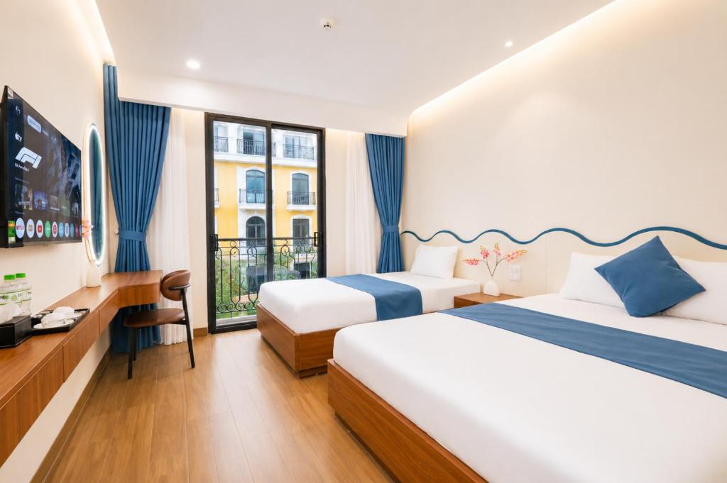 a hotel room with two beds and a television at Sunset Samson Hotel in Sầm Sơn