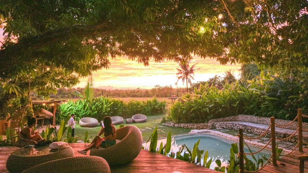 a group of people sitting around a pool in a backyard at JungleNest Resort in General Luna