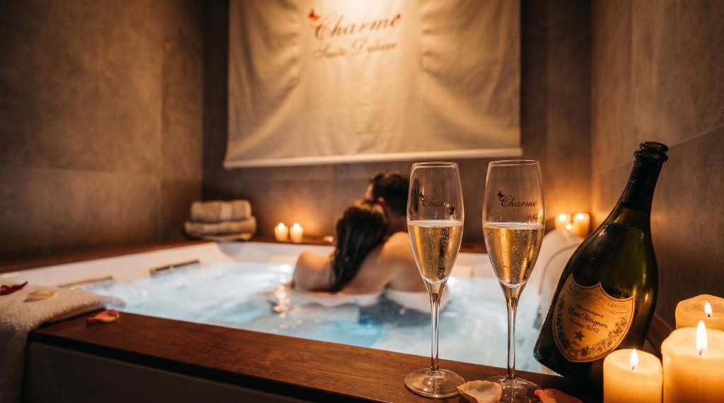 a woman in a bath tub with two champagne glasses at charme suite delux in Terrasini