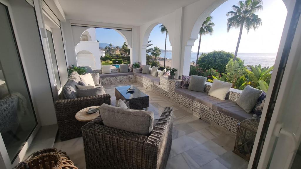 an outdoor patio with couches and chairs and the ocean at 240 Front line beach La Cala in La Cala de Mijas