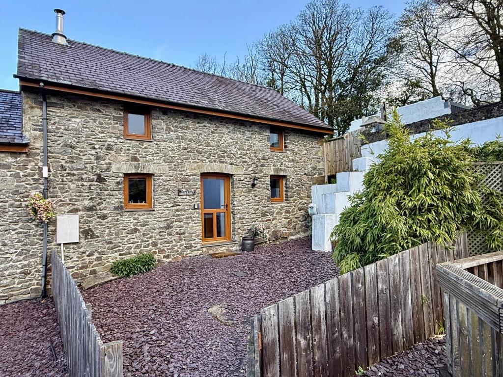 a stone house with a wooden fence in front of it at Millers Cottage in Llandysul