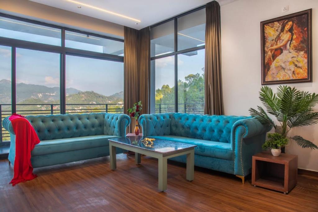a living room with two blue couches and a table at The Royal Apartments Manor I Roof Top Restaurant I Self Cooking Available I Lift I 7o1827o7o3 in Kasauli