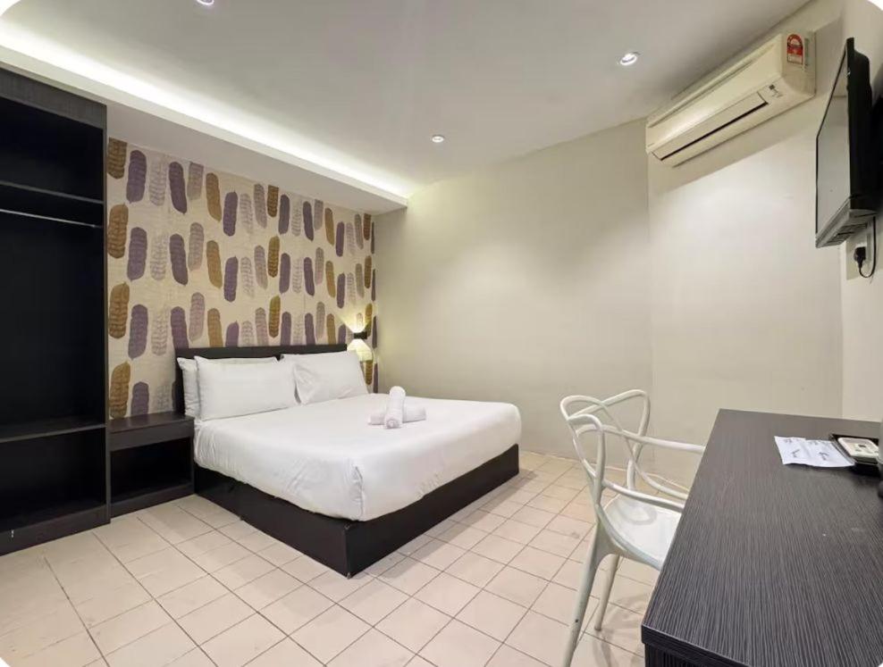 a bedroom with a bed and a table and a desk at Q Inn by Pillow Plus in Petaling Jaya