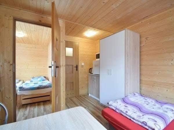 a wooden room with a bedroom with a bed in it at Domki Mucki in Międzywodzie