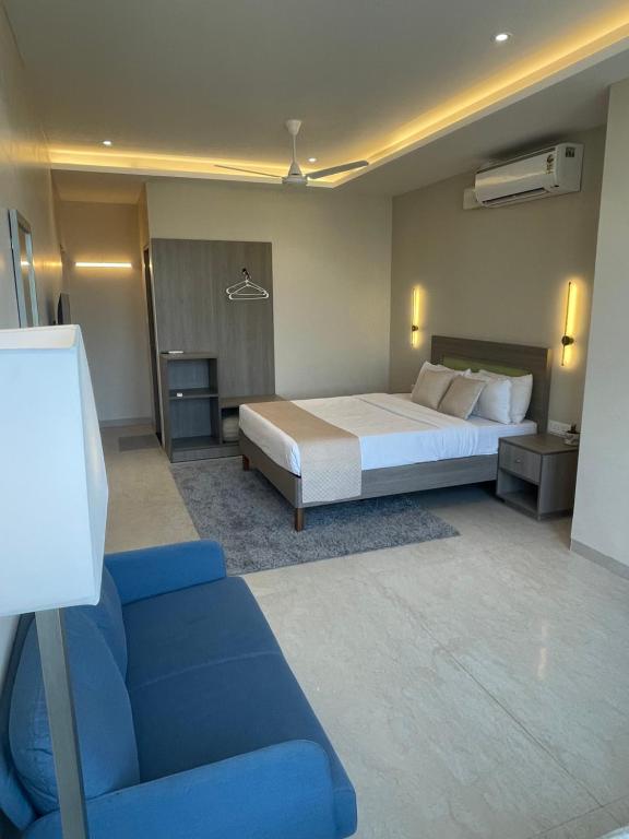 a bedroom with a bed and a blue couch at Raghav Residency in Vellore