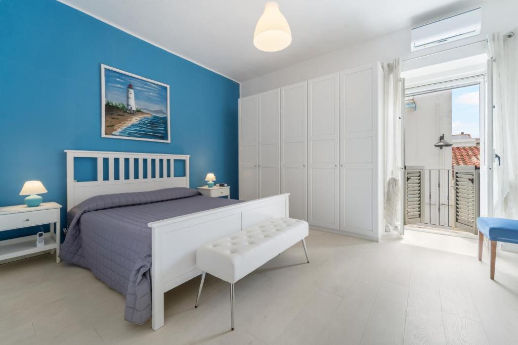a bedroom with blue walls and a bed with a bench at Al centro del Borgo in Calasetta