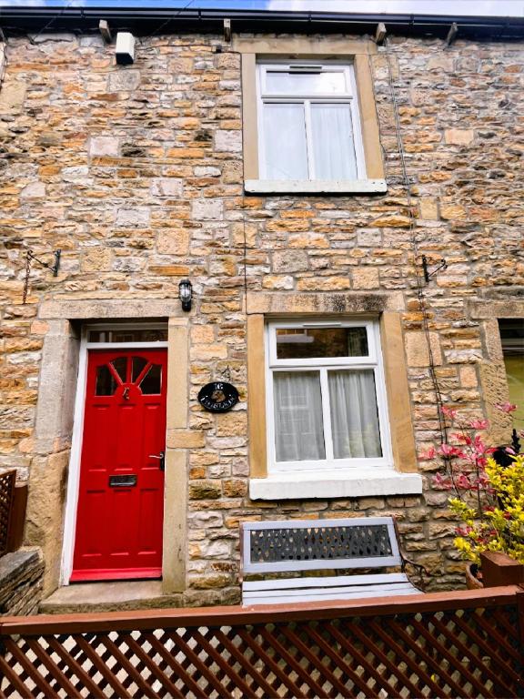 a brick building with a red door and two windows at Dog-Friendly Cottage, Skipton, Thisledo Holiday Cottage in Skipton