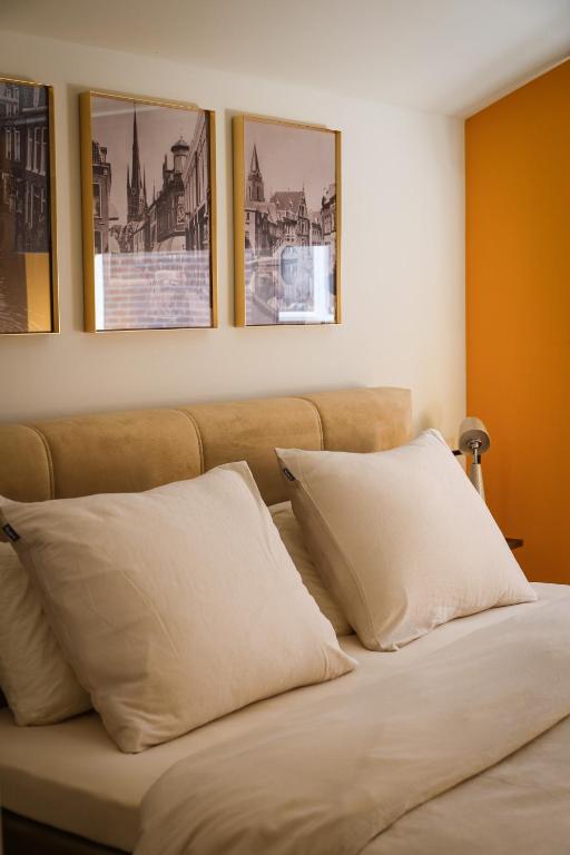 a bed with two pillows and three pictures on the wall at Tiny's Herberg in Woerden