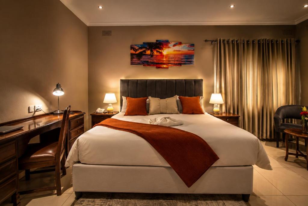 a bedroom with a large bed and a desk and a desk at Kentucky Hotel in Harare