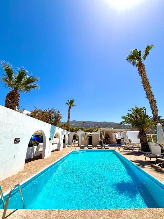 a swimming pool with palm trees next to a building at Marcos Beach in Mylopotas