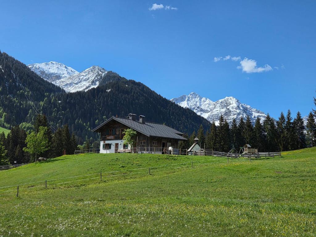 a house on a hill in a field with mountains at Eberlehof in Riezlern