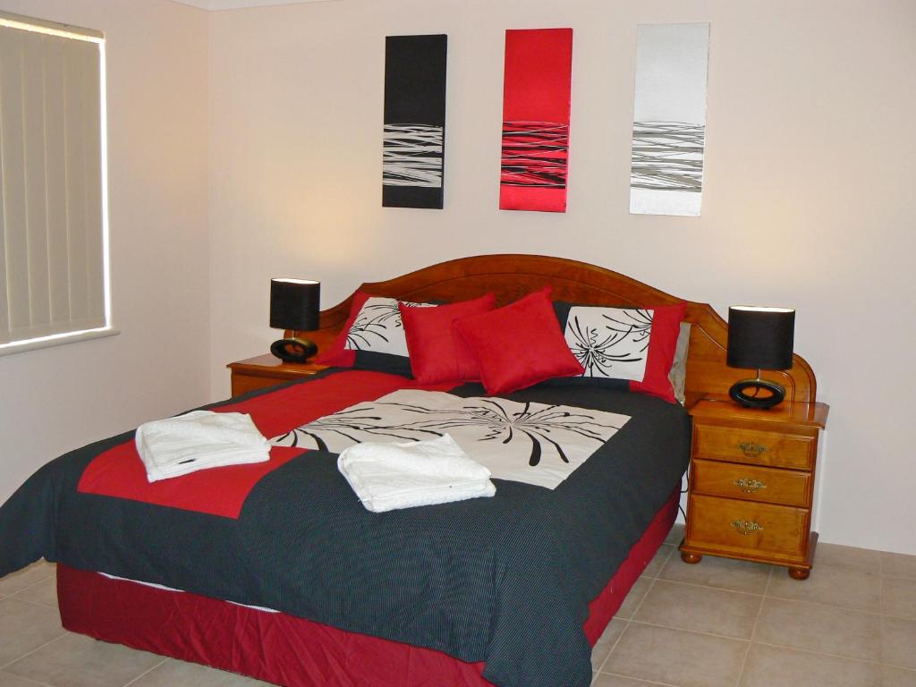Geraldton Luxury Vacation Home with free Streaming في جيرالدتون: غرفة نوم بسرير كبير ومخدات حمراء
