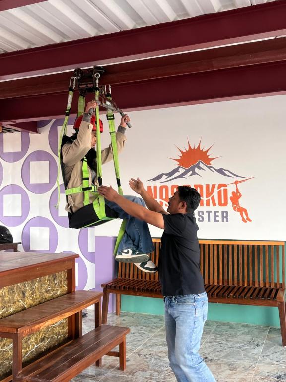 two men are on a rope hanging from a ceiling at Nagarkot Zip Coaster Pvt Ltd in Nagarkot