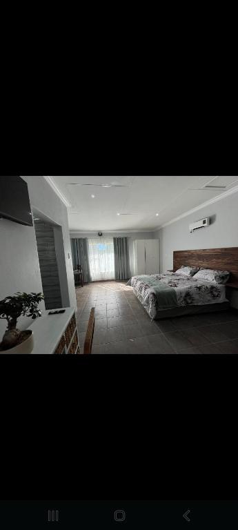 a large bedroom with a bed and a window at Nightingale Guesthouse Randfontein in Randfontein